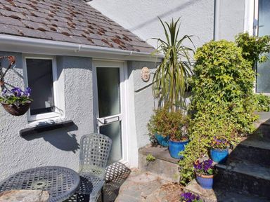 An outdoor area with a table, chair, and potted plants at 1 Bedroom Apartment with Sea View in Mevagissey