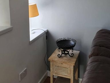 A corner of a living room with a lamp and a table at 1 Bedroom Apartment with Sea View, Mevagissey