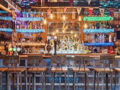 A bar with shelves of bottles and bar stools at 5 Bed House, Sleeps 14 with Hot Tub and Bar Tavistock