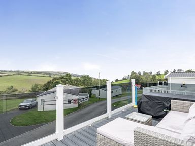 A sitting area with glass railing overlooking hills at Ty dee seaview escapes in Looe