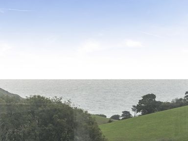 A view of the ocean and hills at Ty dee seaview escapes in Looe