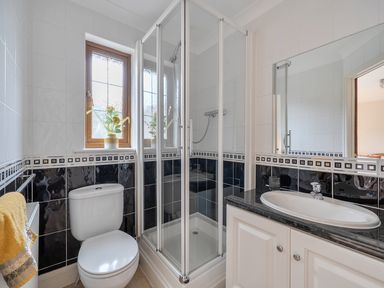 A bathroom featuring a shower, toilet, sink, and window at 2 Bed, Sleeps 4 with Parking and EV charging, Wadebridge