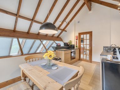 A kitchen with wooden beams and a dining table at 2 Bed, Sleeps 4 with Parking and EV charging in Wadebridge
