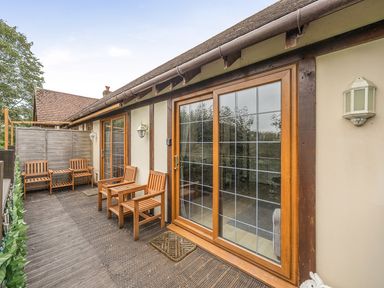 An outdoor area with wooden chairs and large windows at 2 Bed, Sleeps 4 with Parking and EV charging in Wadebridge