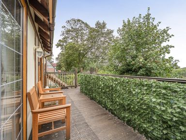 A balcony with wooden chairs and greenery at 2 Bed, Sleeps 4 with Parking and EV charging Wadebridge