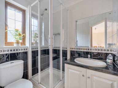 A bathroom with a shower, sink, toilet, and window at 2 Bed, Sleeps 4 with Parking and EV charging in Wadebridge