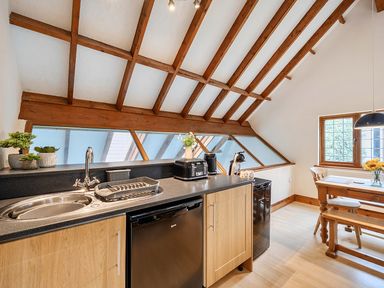 A kitchen with a sink, refrigerator, coffee maker, and dining table at 2 Bed, Sleeps 4 with Parking and EV charging in Wadebridge