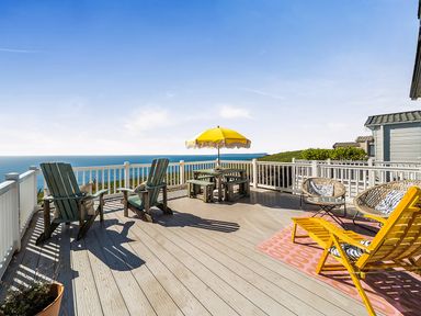 A deck with seating and a table with an umbrella at 2 Bed Caravan, Sleeps 4 with Sea Views, West Lulworth