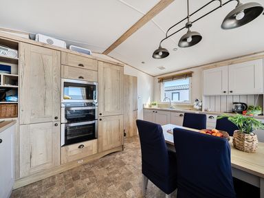 A kitchen with an oven and dining table at 2 Bed Caravan, Sleeps 4 with Sea Views West Lulworth