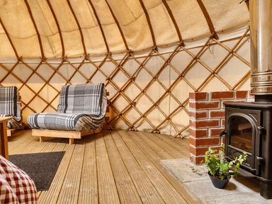 A seating area with armchairs and a wood stove at Yurt, Sleeps 2 with BBQ and Fire Pit, Tregooden Farm near St Tudy