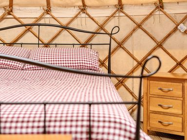 A bedroom with a bed and nightstand at Yurt, Sleeps 2 with BBQ and Fire Pit, Tregooden Farm near St Tudy