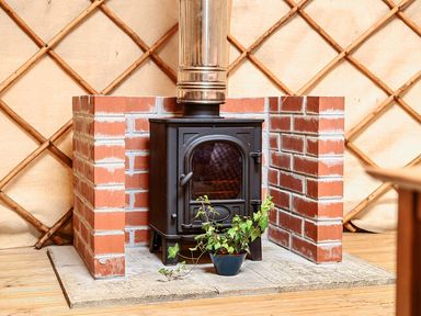 A snug with a stove and plant at Yurt, Sleeps 2 with BBQ and Fire Pit, Tregooden Farm near St Tudy