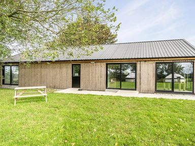 A building with large windows and a table in an outdoor area at Yurt, Sleeps 5 and Dogs Welcome