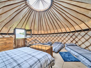 A bedroom with beds and furniture in a Yurt, Sleeps 5 and Dogs Welcome