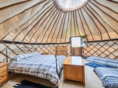 A bedroom with beds and furniture in a Yurt, Sleeps 5 and Dogs Welcome