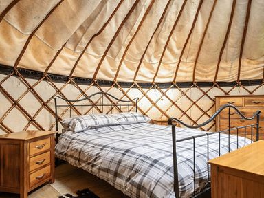 A bedroom with a bed and nightstands at Yurt, Sleeps 5 and Dogs Welcome