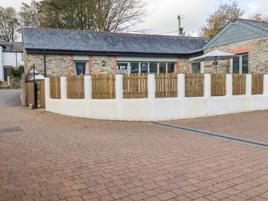 An exterior view of a stone building with a fence and umbrella at The Old Dairy in 