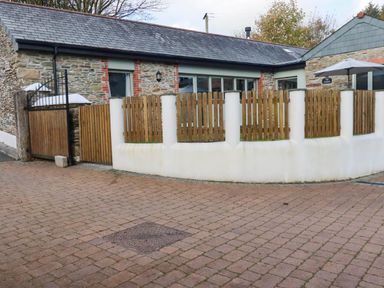 An outdoor area with a stone building and wooden fence at The Old Dairy 