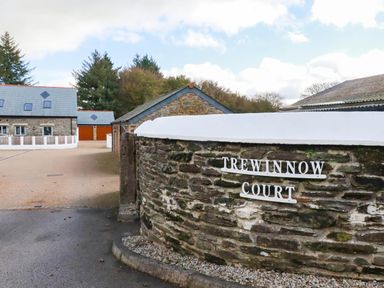An entrance with a stone wall and buildings at Trewinnow Court in 