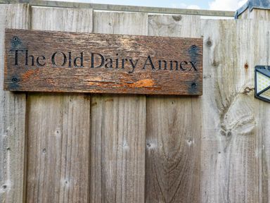 A wooden sign on a fence stating The Old Dairy Annex