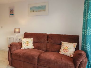 A living room with a brown sofa and wall art at The Old Dairy in Wadebridge