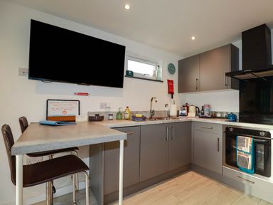 A kitchen with cabinets, sink, oven, and TV at The Old Dairy in Wadebridge