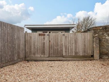 A wooden gate and fence in front of a building at The Old Dairy in Wadebridge