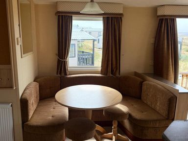 A dining area with a round table and seating at Haven Perransands, 575 Perranporth