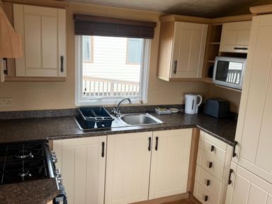 A kitchen with sink, stove, microwave, kettle, and toaster at Haven Perransands, 575, Perranporth