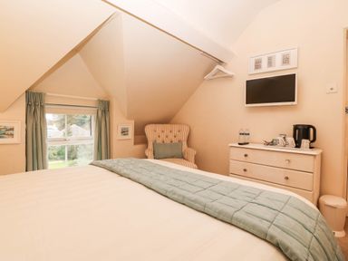 A bedroom with an armchair and television at Craig Y Glyn