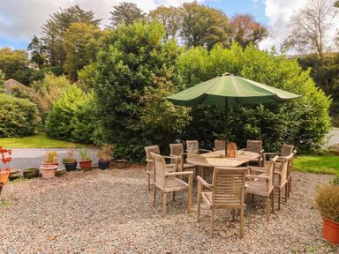A dining table with chairs and an umbrella in an outdoor space at Craig Y Glyn