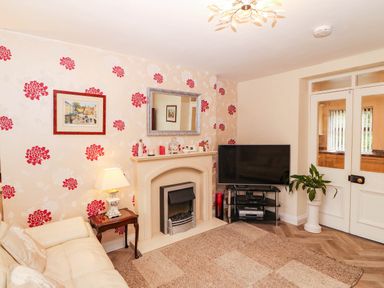 A living room with a television and sofa at Craig Y Glyn Cottage in Pwllheli