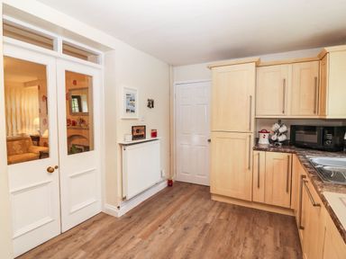 A kitchen with cabinets and a microwave at Craig Y Glyn Cottage in Pwllheli