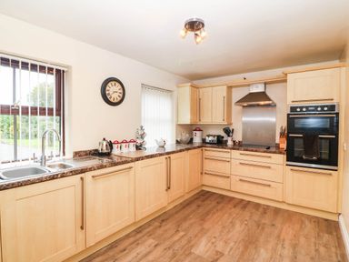 A kitchen with a clock and appliances at Craig Y Glyn Cottage Pwllheli