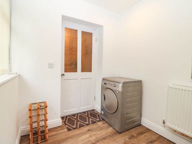 A utility room with a dryer and door at Craig Y Glyn Cottage Pwllheli