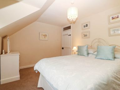 A bedroom with a bed and wardrobe at Craig Y Glyn Cottage in Pwllheli