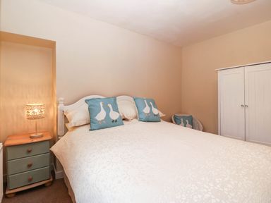 A bedroom with a bed and side table at Craig Y Glyn Cottage in Pwllheli