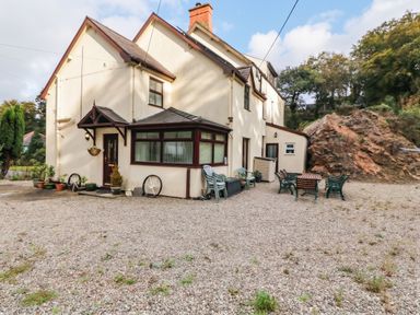 An outdoor area with a house and seating at Craig Y Glyn Cottage in Pwllheli