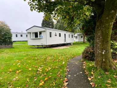 A mobile home in a campground with a pathway and trees at Hafan y Mor - 159 Snowdonia, Pwllheli