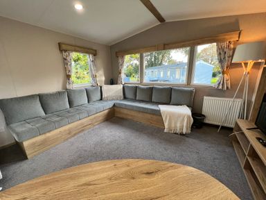 A living room with a corner sofa and coffee table at Hafan y Mor - 159 Snowdonia Pwllheli