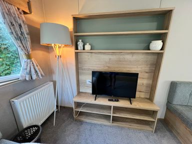 A living room with a television and lamp at Hafan y Mor - 159 Snowdonia Pwllheli
