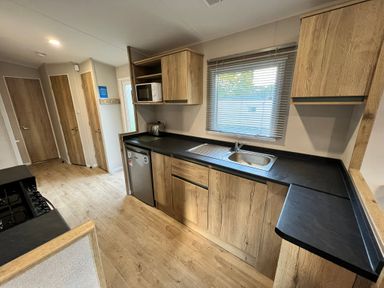 A kitchen with cabinets, sink, stove, and microwave at Hafan y Mor - 159 Snowdonia in Pwllheli
