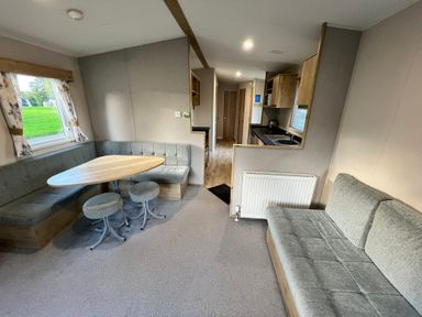 A living room with a dining area and kitchen in Hafan y Mor - 159 Snowdonia Pwllheli