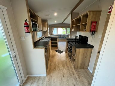 A kitchen with cabinets and appliances at Hafan y Mor - 159 Snowdonia in Pwllheli