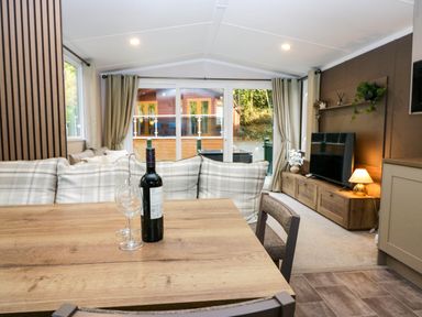 A living room with a dining table and wine bottle at Lake It Easy Troutbeck Bridge