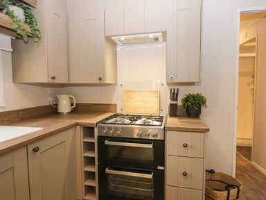 A kitchen with cabinets, stove, and sink at Lake It Easy in Troutbeck Bridge