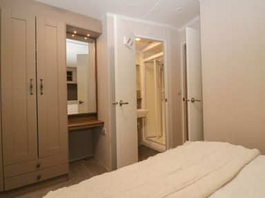 A bedroom with a wardrobe and a bathroom entrance at Lake It Easy in Troutbeck Bridge