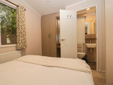 A bedroom with a bed and adjoining bathroom at Lake It Easy, Troutbeck Bridge