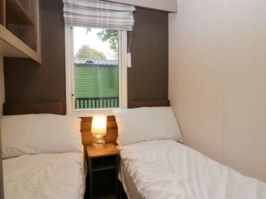 A bedroom with two single beds and a lamp at Lake It Easy, Troutbeck Bridge