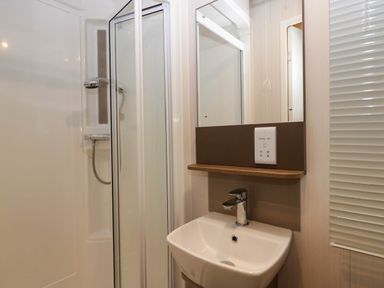 A bathroom with a shower, sink, and mirror at Lake It Easy, Troutbeck Bridge